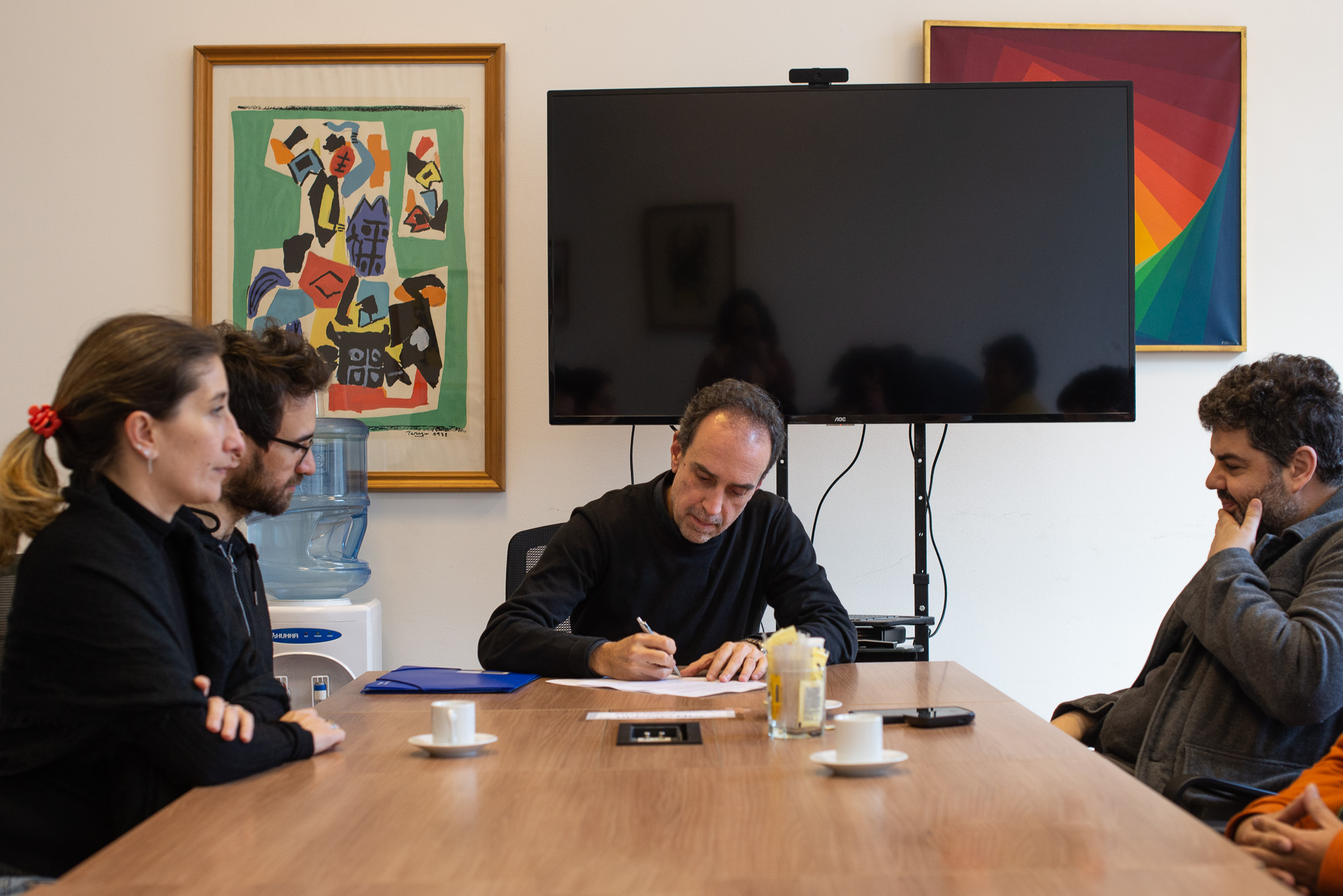 Fotografía donde se ve de frente al decano Fernando Miranda firmando el acuerdo académico, a la izquierda se ve a Gonzalo Varela y Varenka Parentelli y a la derecha se ve a Miguel Olivetti.