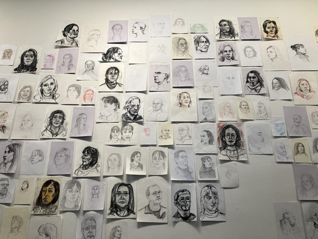 Imagen de la muestra Dando la cara, donde se ven las ilustraciones, retratos de las personas que trabajan en Facultad de Artes.