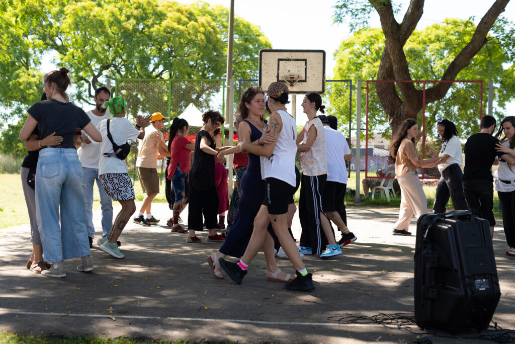 En la fotografía se ve el espacio de una cancha de básquetbol con muchas personas bailando durante la jornada.