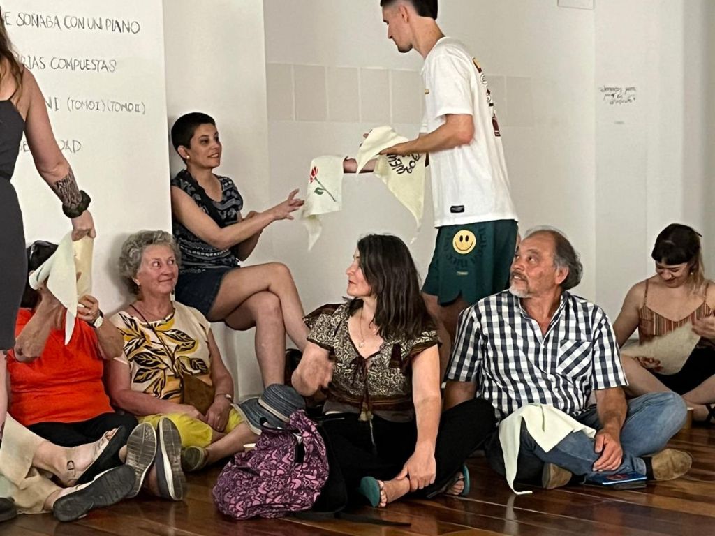 Fotografía en la que puede ver a un estudiante entregando a los participantes los pañuelos triangulares.