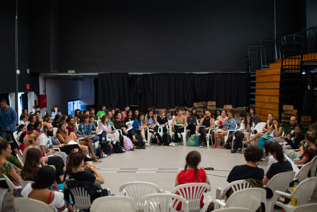 Fotografía de una ronda importante de personas sentadas, escuchando y participando de la charla de Ray Chung