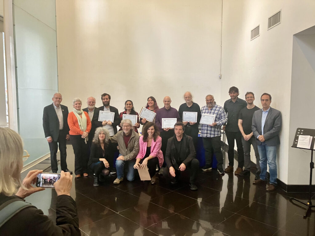 Foto de familia de los magísteres con sus títulos en mano, junto a autoridades de Facultad de Artes.