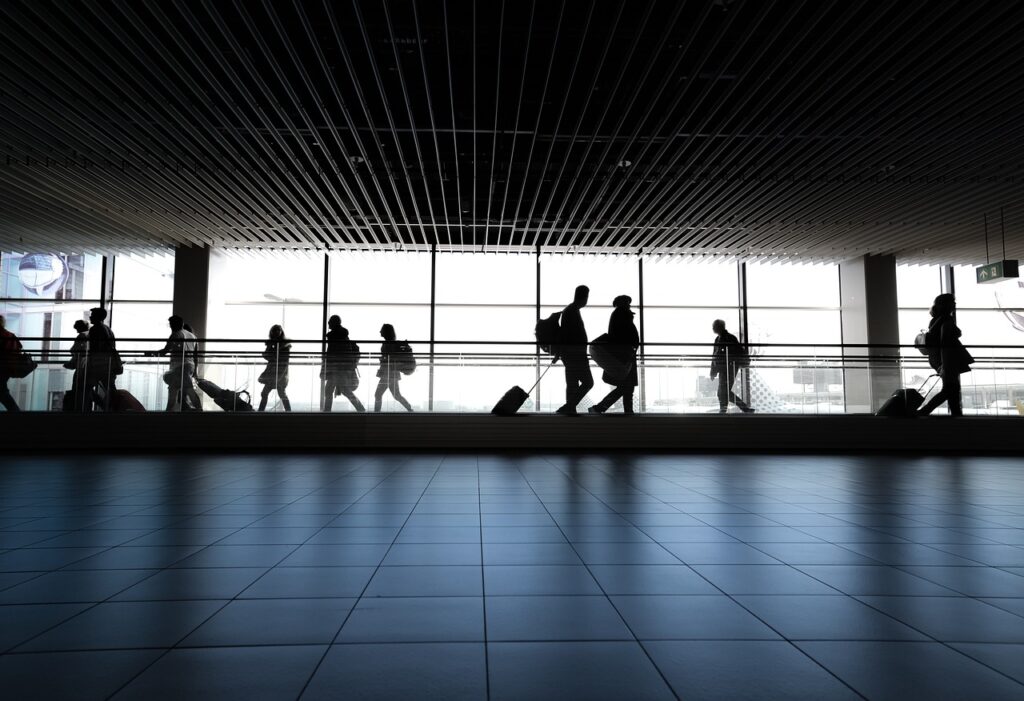 A contraluz se ven personas en tránsito de aeropuerto