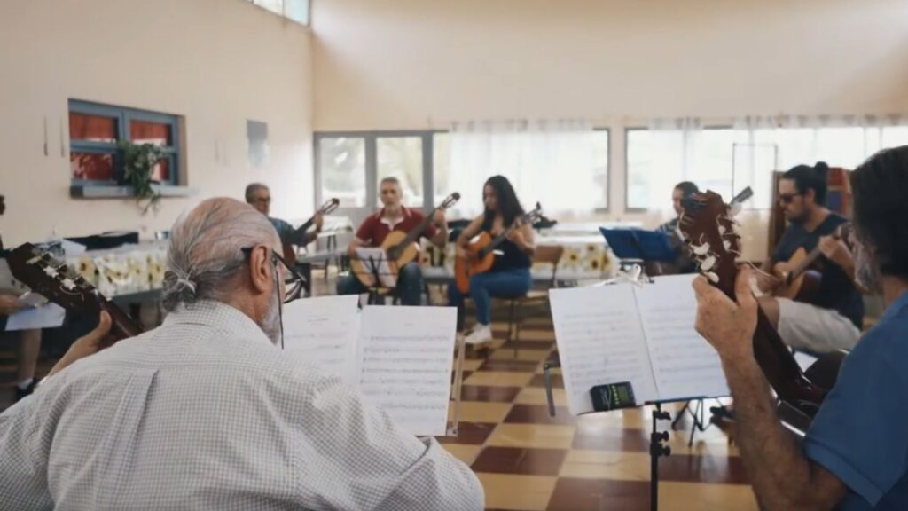 Grupo de personas sentadas en ronda tocando la guitarra