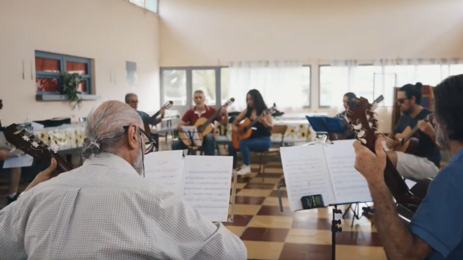 Grupo de personas sentadas en ronda tocando la guitarra