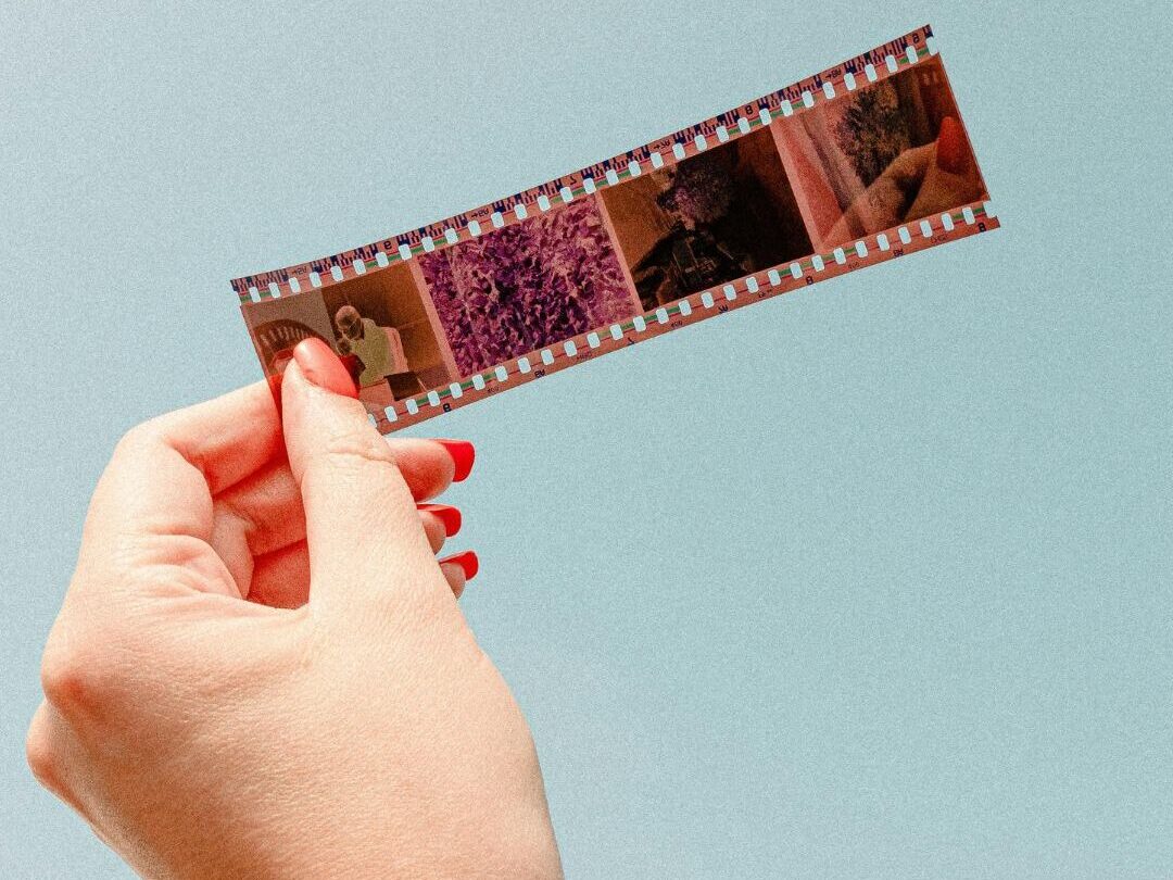 Imagen de una mano sosteniendo un fragmento de negativo fotográfico a contraluz, con fondo celeste