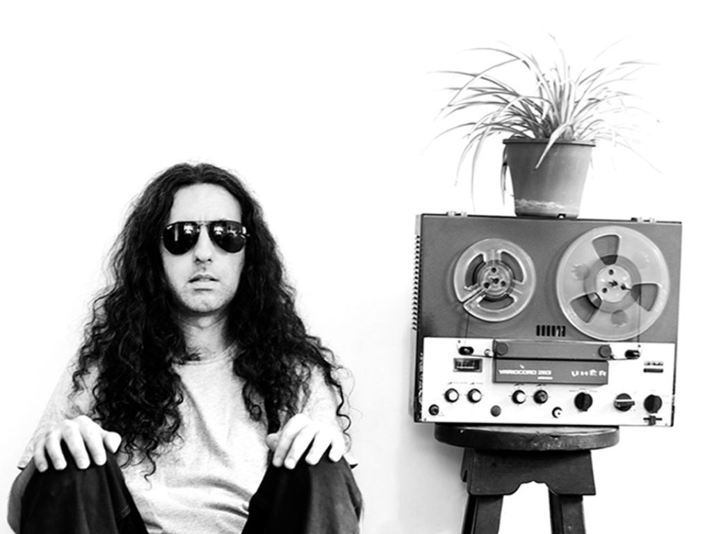 Retrato en blanco y negro de Alan Courtis junto a un grabador de cinta y una planta.