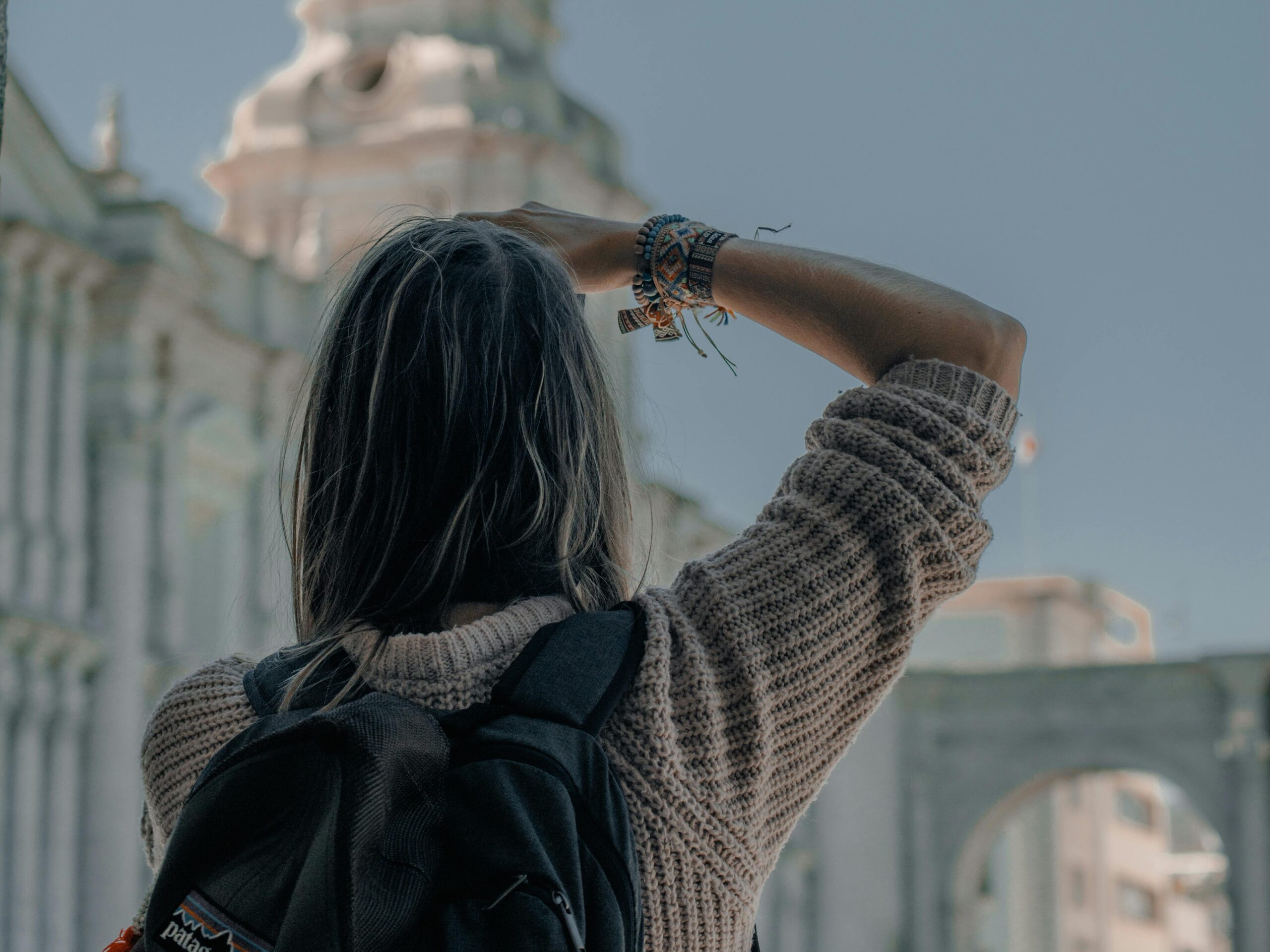 A woman photographs a historic church tower in Arequipa, Peru, highlighting urban exploration.